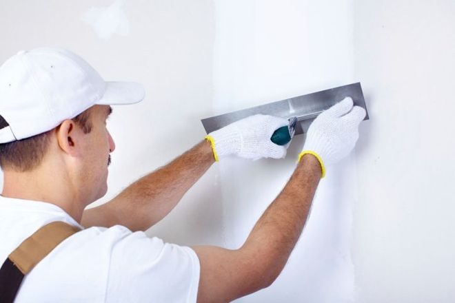 a man is plastering a wall with a spatula