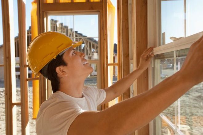 a construction worker is installing a window in a house under construction