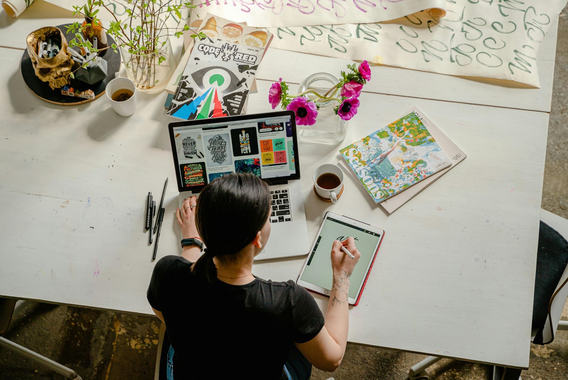 A woman is sitting at a table with a laptop and a tablet.