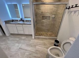 A bathroom with a toilet , sink and shower.