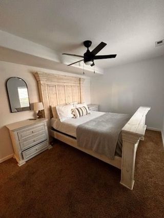 A bedroom with a bed , nightstand , mirror and ceiling fan.