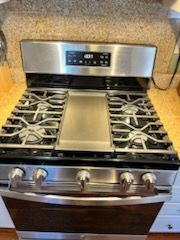 A stainless steel stove top oven is sitting on top of a counter in a kitchen.