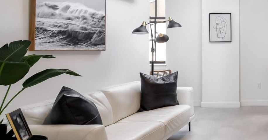 A living room with a white couch and black pillows.