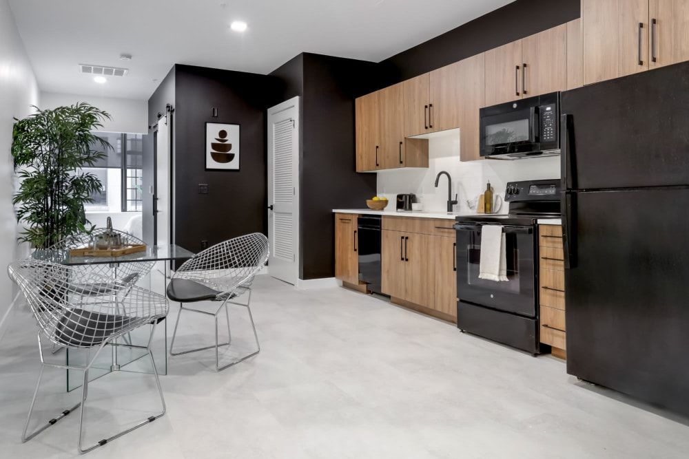 A kitchen with a refrigerator , stove , microwave , sink and chairs.