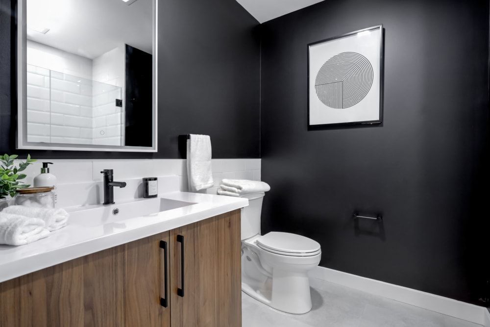 A bathroom with a sink , toilet , mirror and black walls.