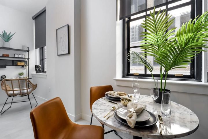 A dining room with a table and chairs and a window.