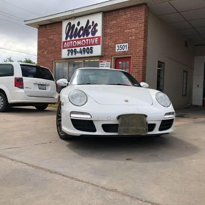 A white car is parked in front of a brick building.