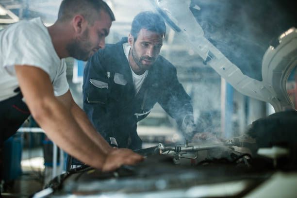 Auto mechanics working on overheated car engine in a workshop