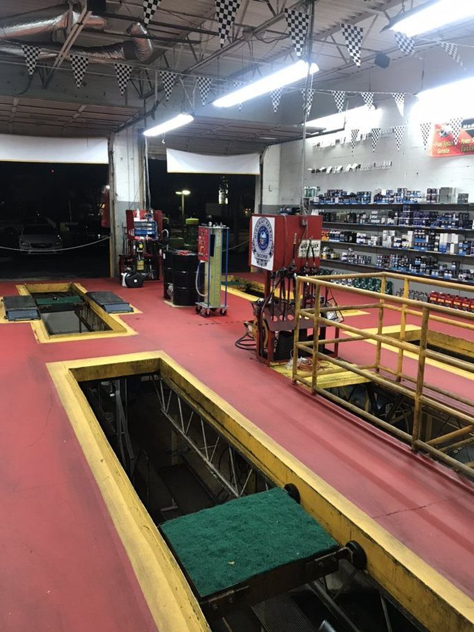 Auto repair shop interior with lifts, tools, parts, and checkered flags. Red floor, yellow accents | Star Quick Lube & Auto Care Center