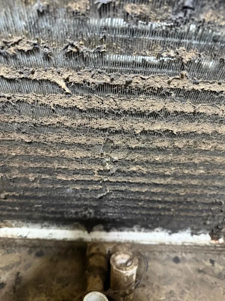Close-up of a dirty, damaged metal radiator or heat exchanger with bent fins and corrosion