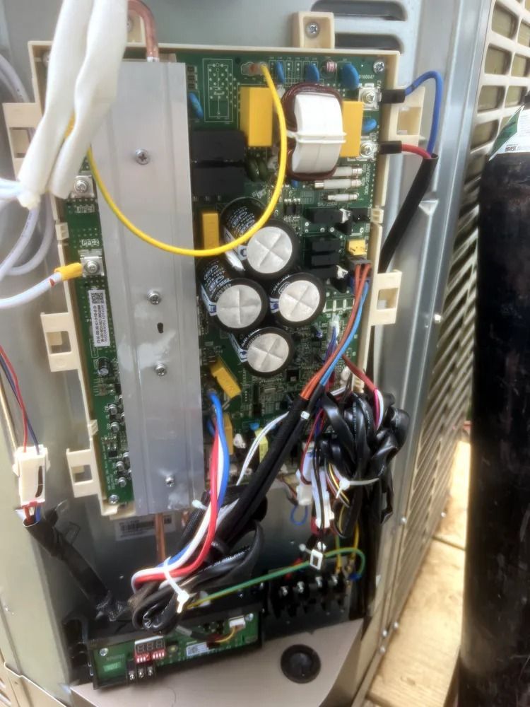 Open electronics cabinet with circuit boards, wires, and large capacitors inside a metal enclosure