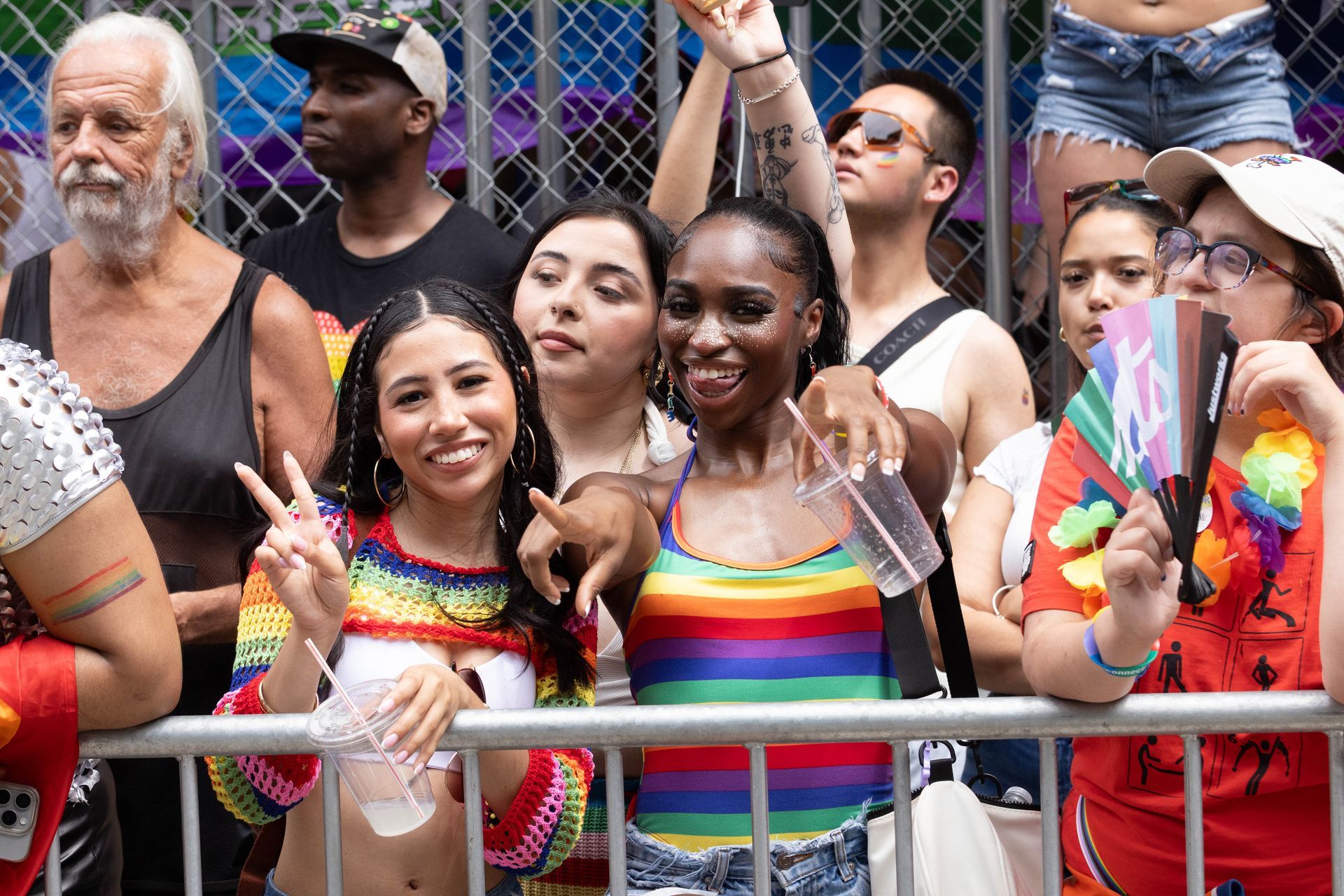 People celebrating at a Pride parade; smiling, with rainbow clothing and accessories.