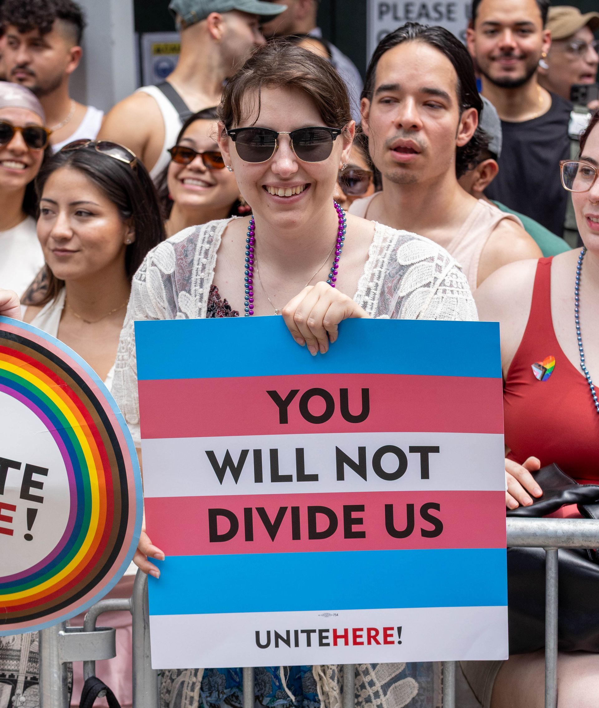 Person holding a sign with transgender flag colors, 