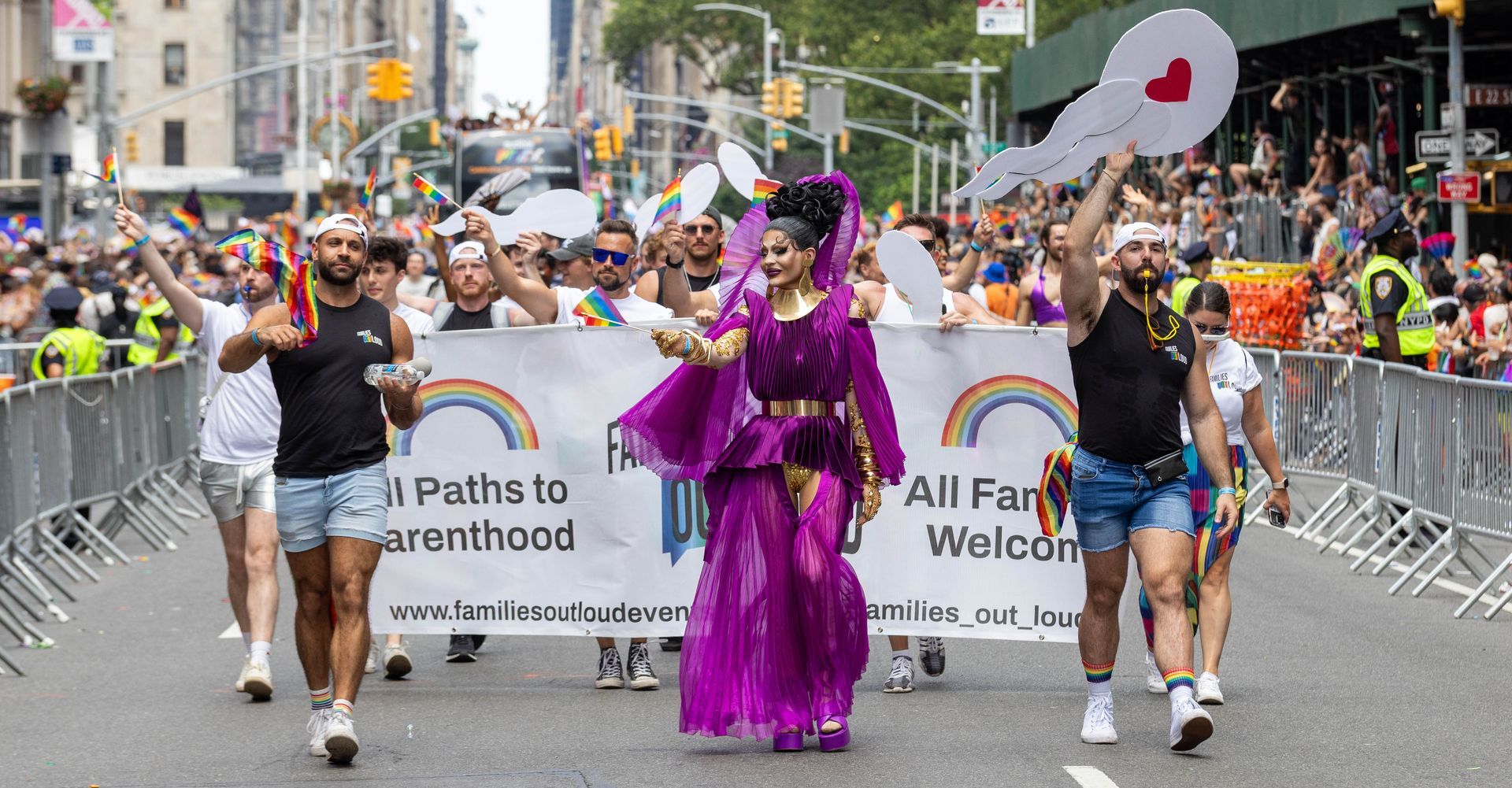 Pride parade with a person in a purple outfit, banner 