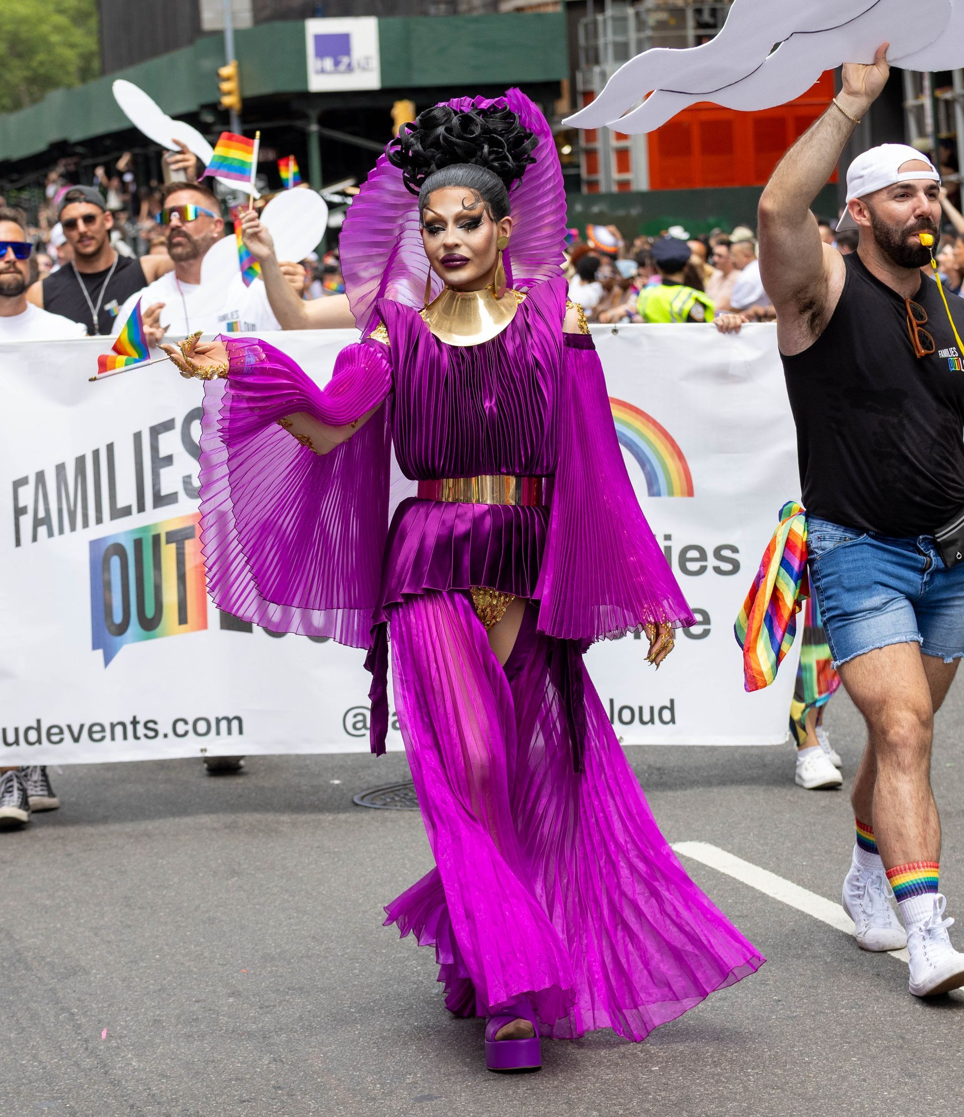 Person in purple drag outfit at a pride parade.