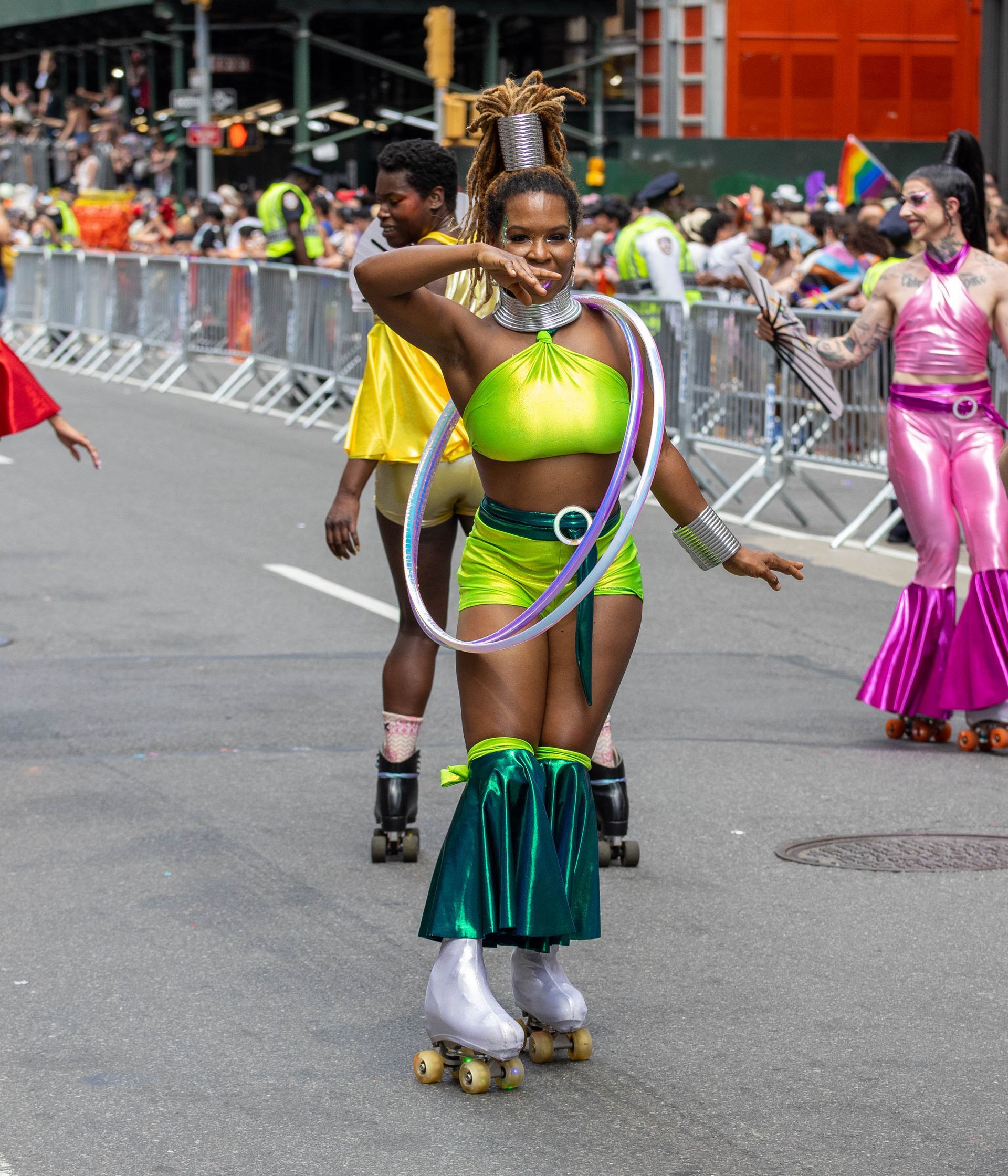 Woman on roller skates wearing neon green outfit, performing at a Pride parade.