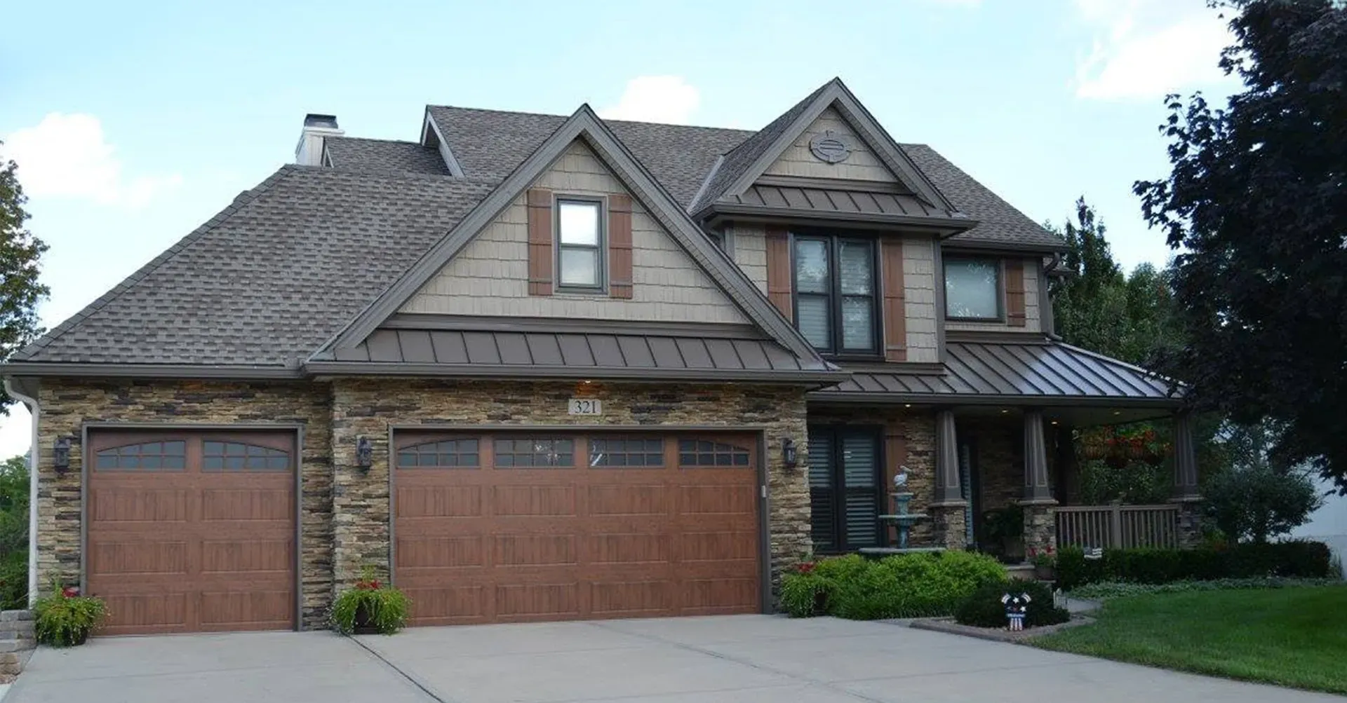 A large house with two garage doors and a metal roof