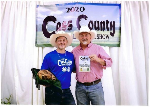 Two men standing in front of a sign that says cross county show