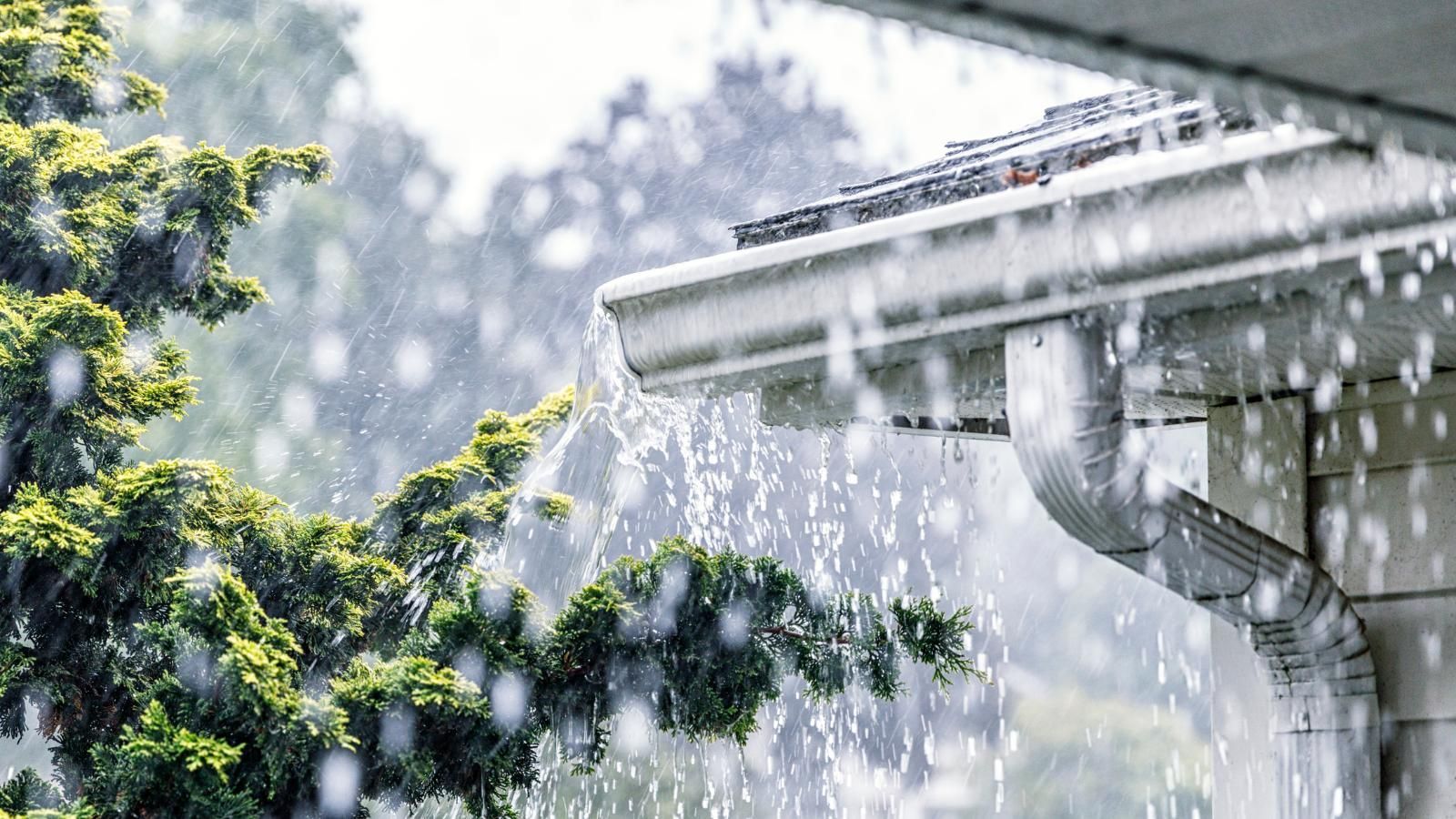 Rain is falling from the gutters of a house.