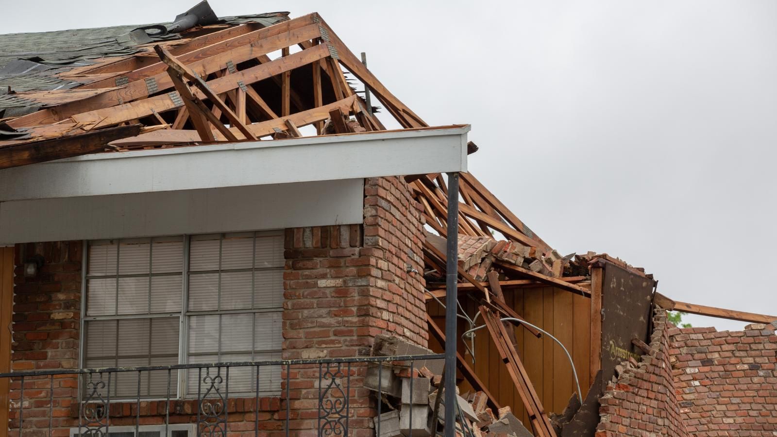 A brick house with a roof that has been damaged by a tornado.