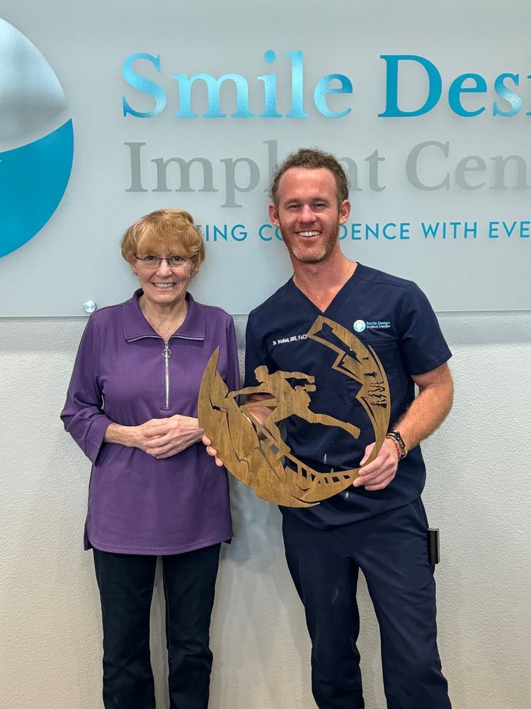 Woman and man in a dental office holding a mountain-themed award.