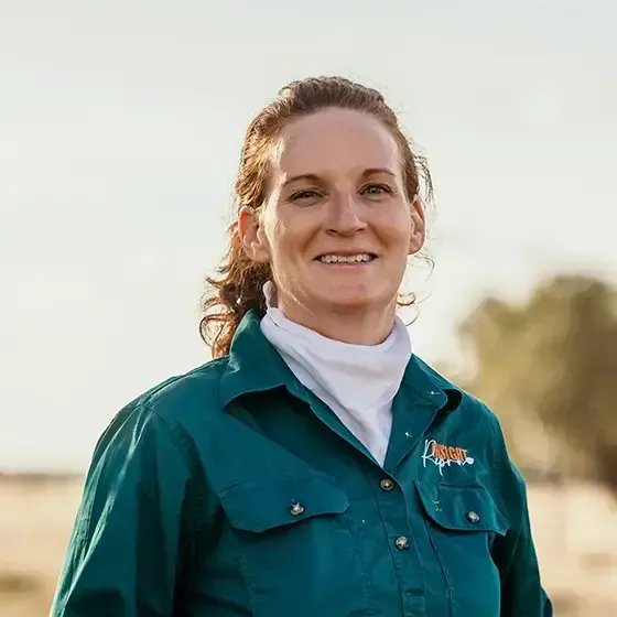 A woman in a green shirt and white turtleneck is smiling for the camera.
