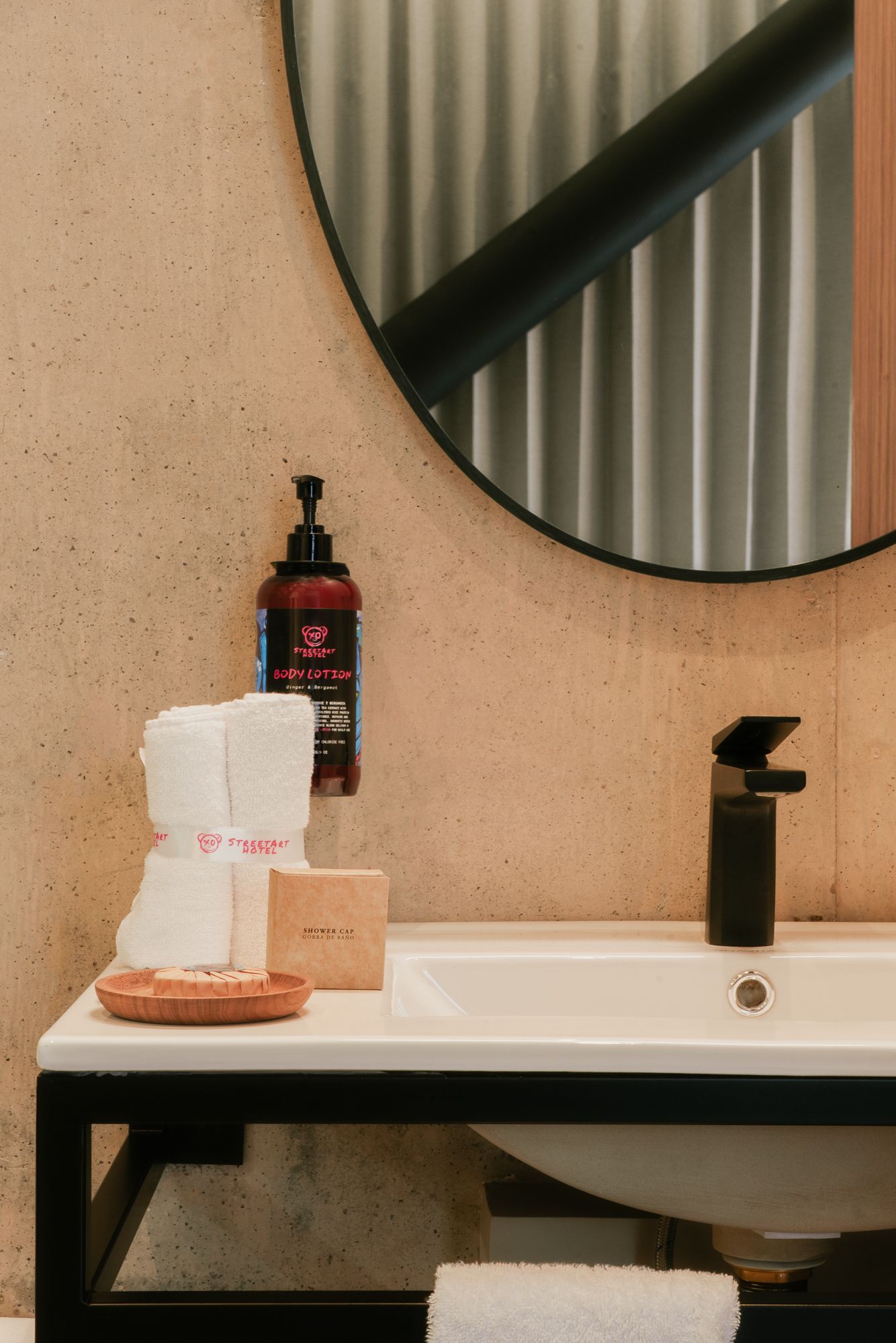 Bathroom sink with black faucet, mirror, towels, and soap dispenser.