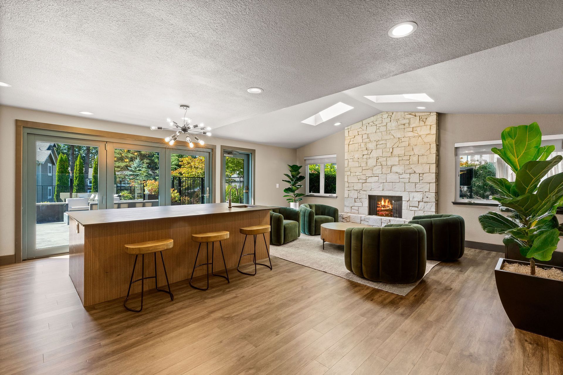 Spacious open living area with kitchen island, fireplace, and large windows.