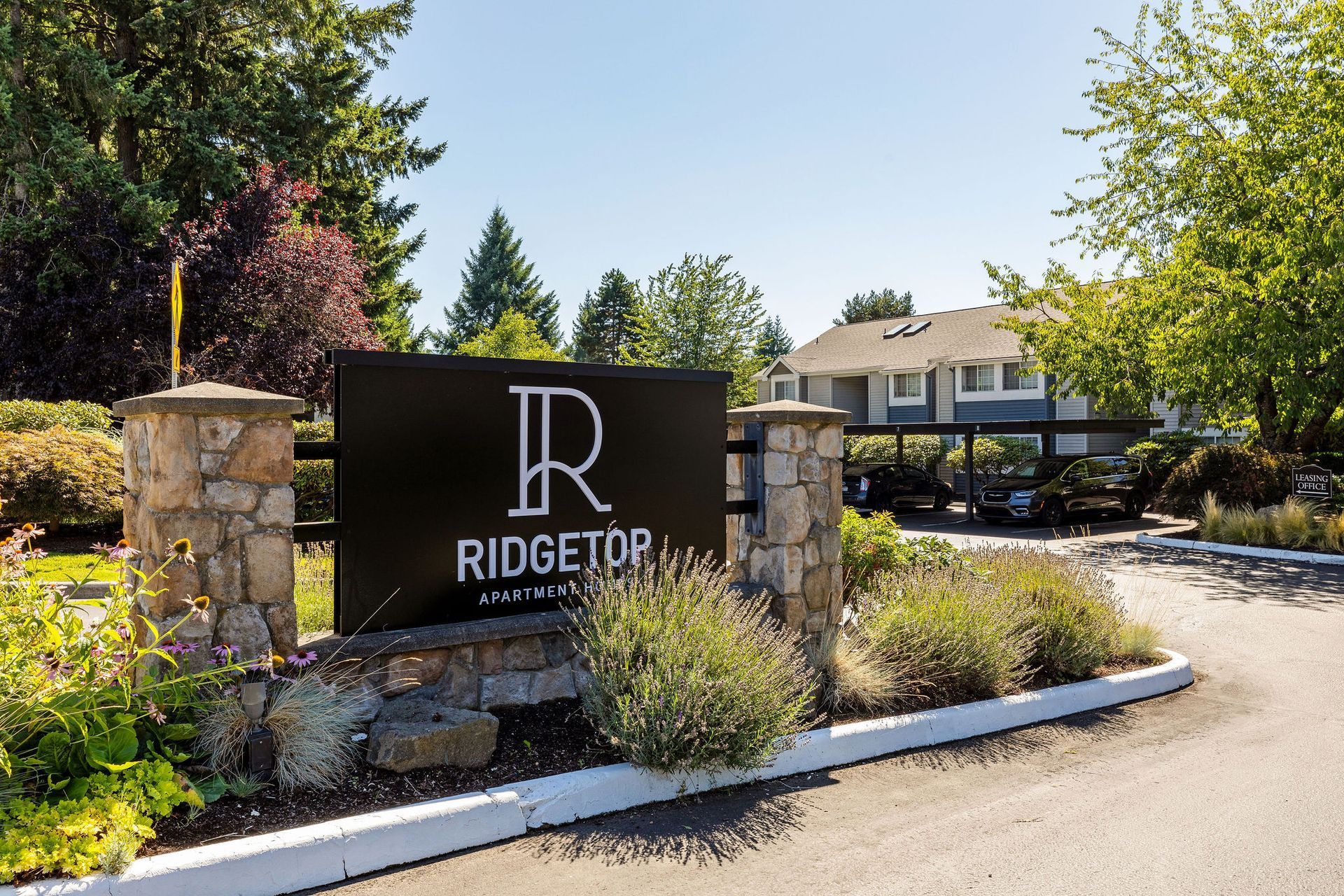 Sign for Ridgetop Apartments, black with white text, set in landscaping and stone pillars.