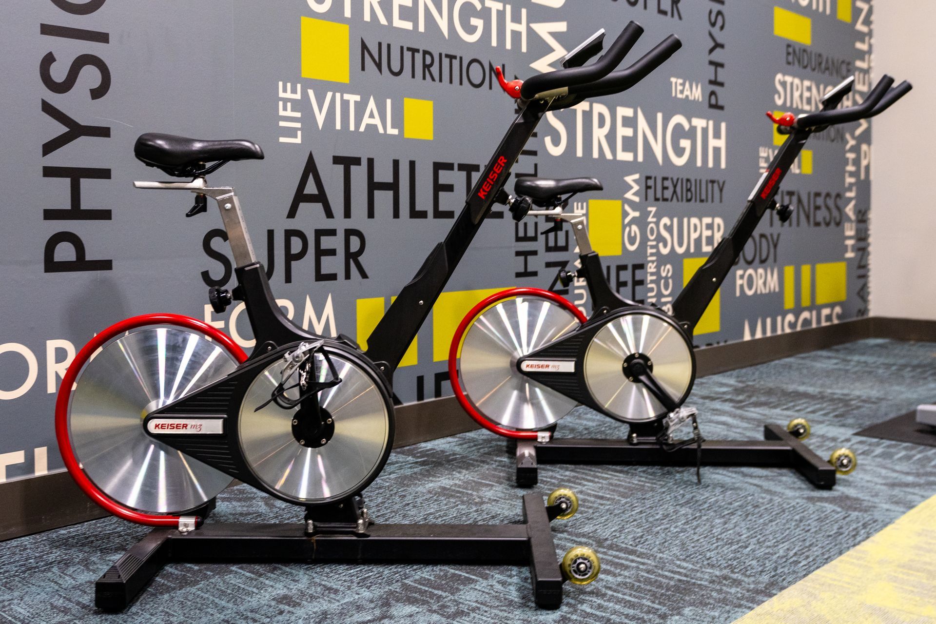 Two exercise bikes are sitting in front of a wall with words on it