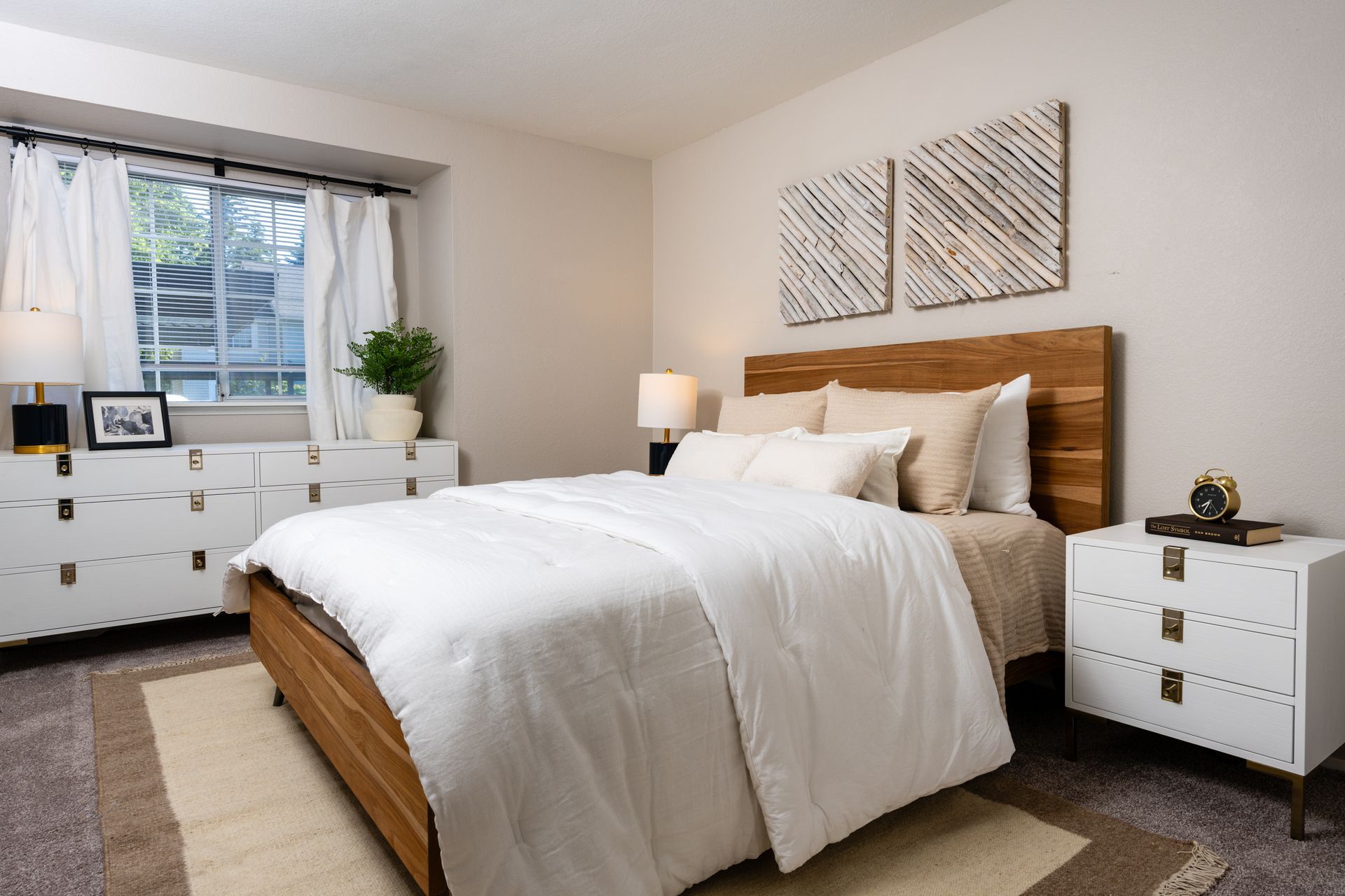A bedroom with a bed , nightstand , dresser and window.