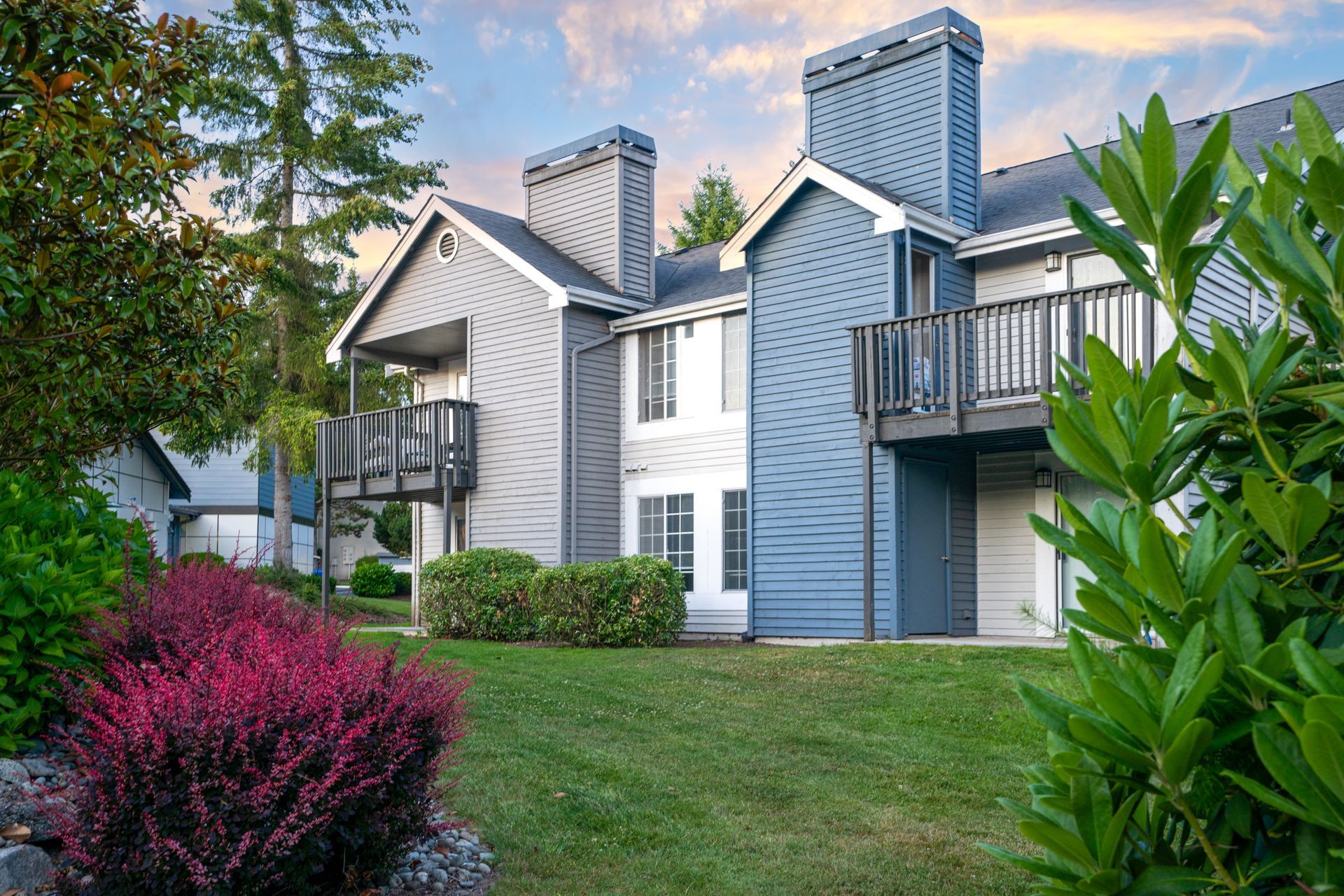 A large apartment building with a lush green lawn in front of it.