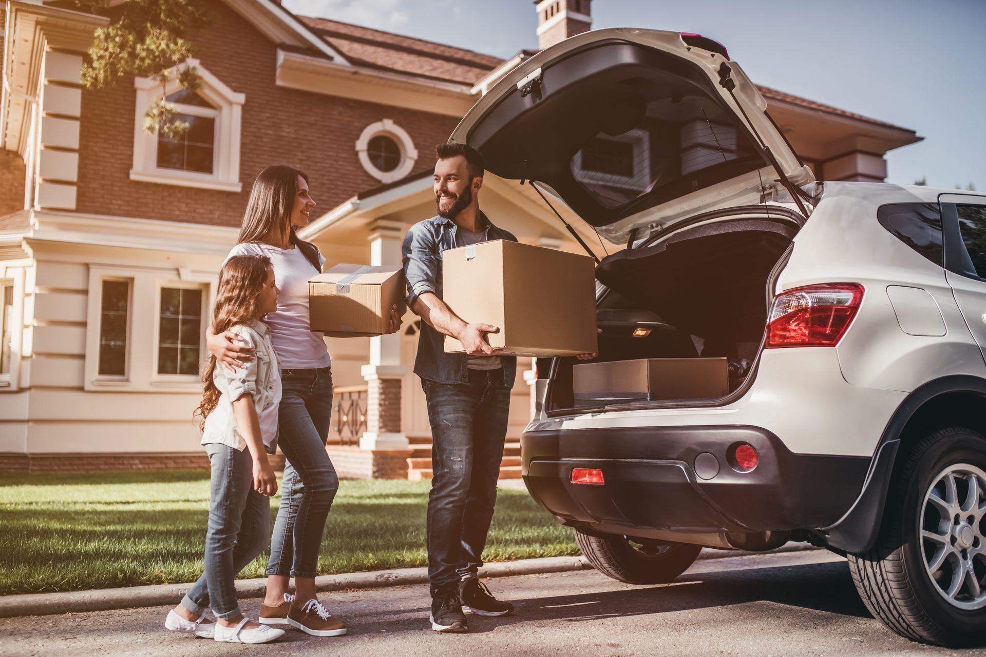 Family loading boxes into a car in front of their new house.