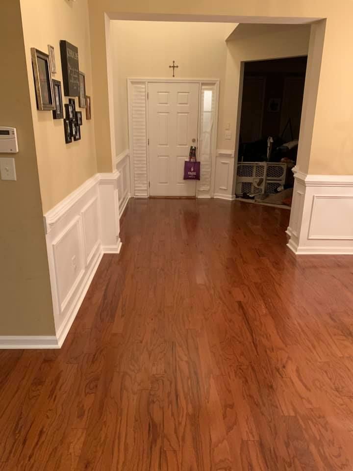 A hallway with hardwood floors and a cross on the wall.