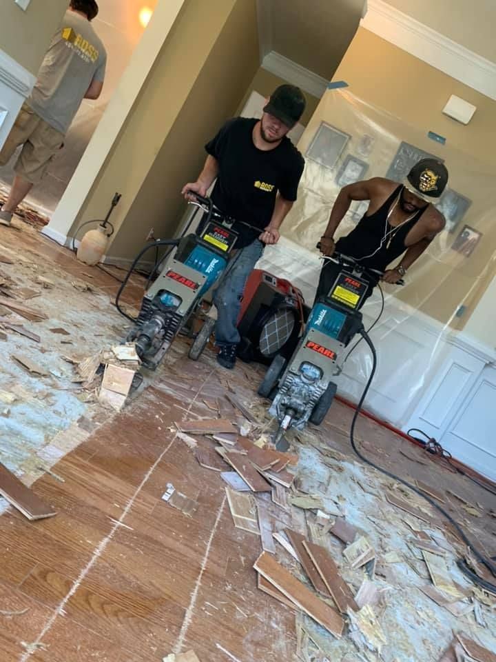 Two men are working on a wooden floor with a machine.