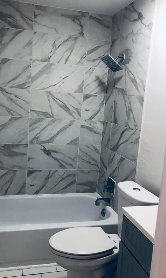 A bathroom with a toilet , bathtub and shower.