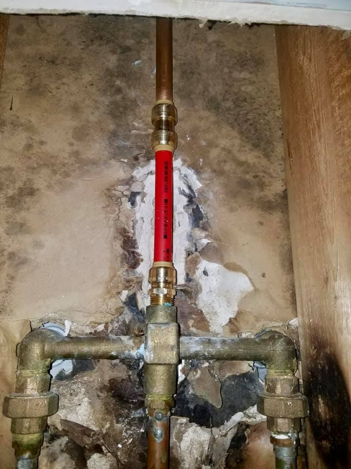 A close up of a copper pipe in a hole in a wall.