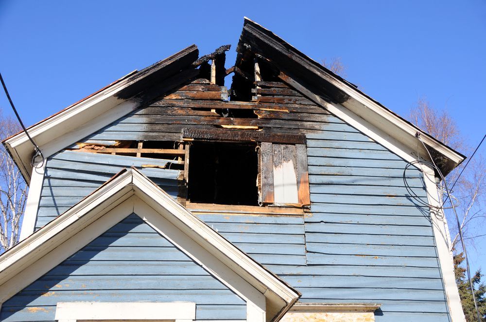 A blue house with a roof that has been damaged by fire