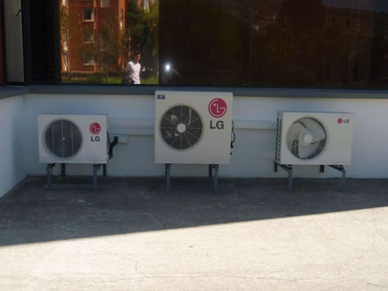 Tres acondicionadores de aire están alineados en el costado de un edificio.