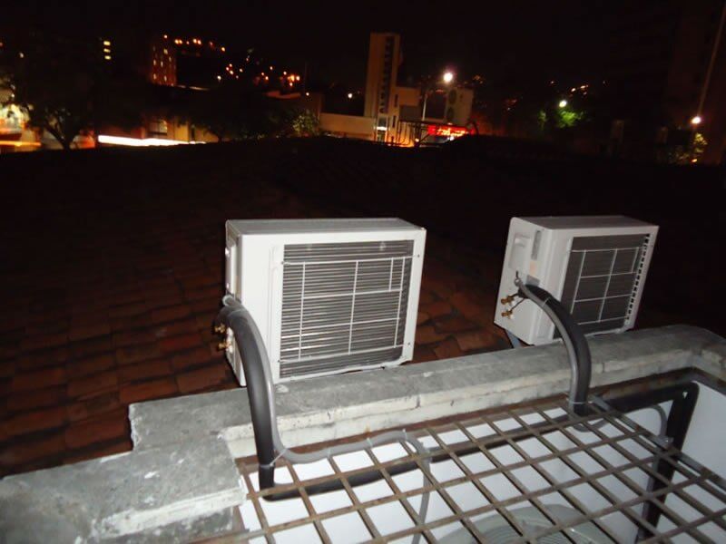 Dos aparatos de aire acondicionado están en el tejado de un edificio por la noche.
