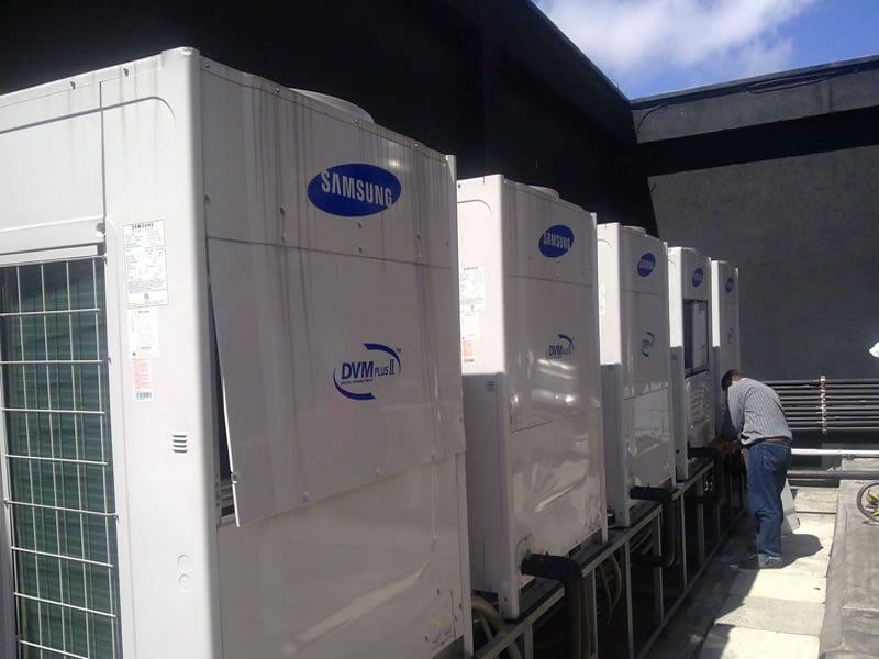 Un hombre está trabajando en una fila de acondicionadores de aire.