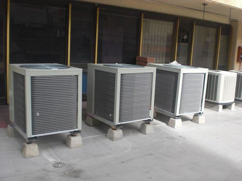 Una fila de aparatos de aire acondicionado están alineados frente a un edificio.