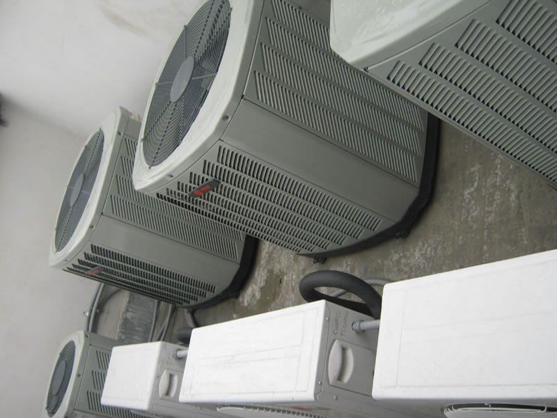 Una fila de aparatos de aire acondicionado están alineados en una pared.