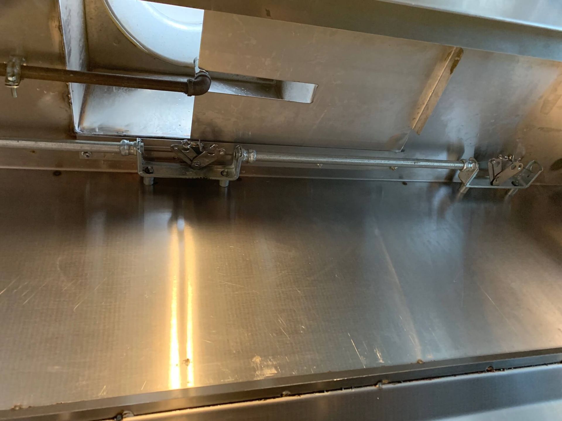 A close up of a stainless steel wall with a sink in the background.