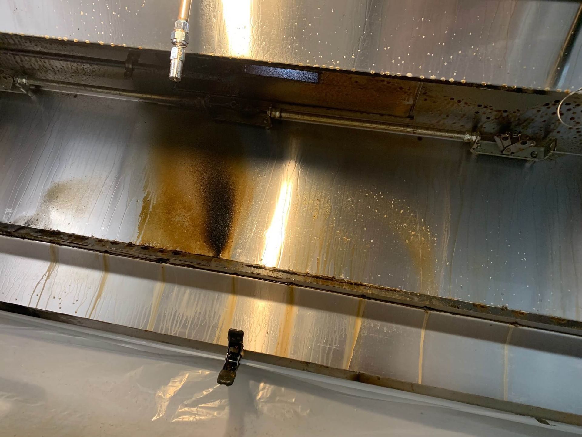 A close up of a stainless steel hood with a lot of stains on it.