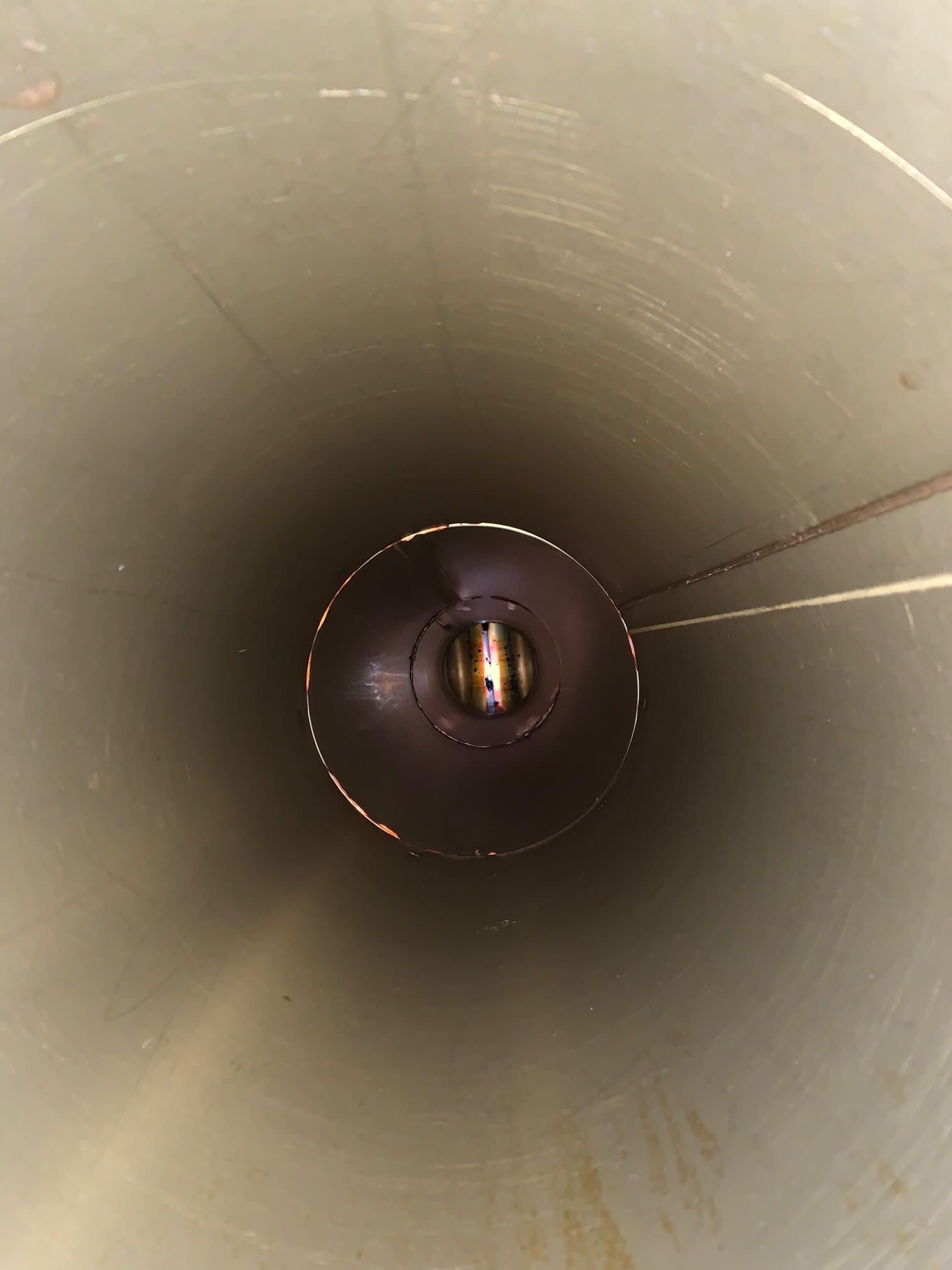 The inside of a metal pipe with a hole in the middle.