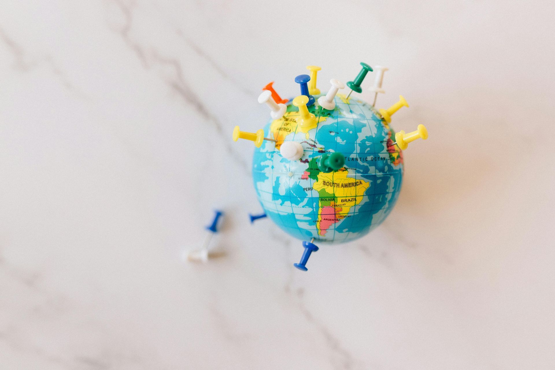 A small globe surrounded by pins on a table.