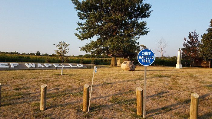 Chief Wapello memorial site featuring a large tree, stone monument, and a blue 