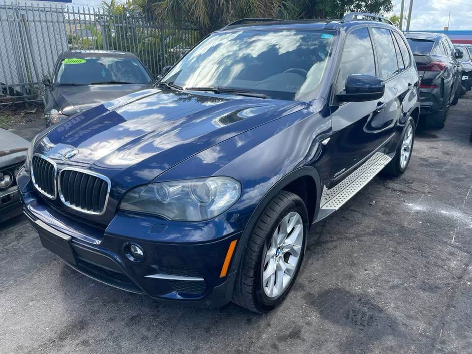 A blue bmw x5 is parked in a lot.
