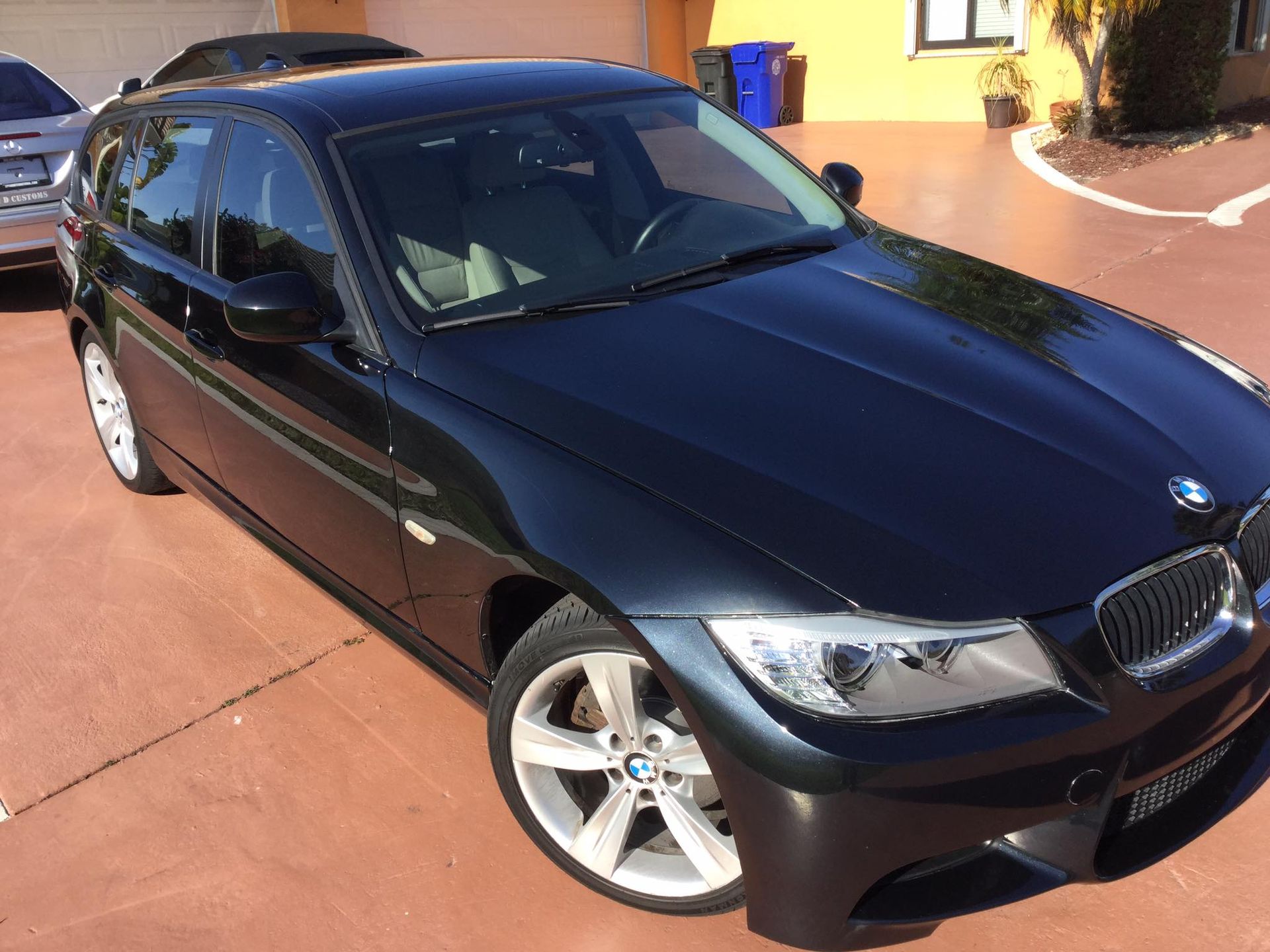 A black bmw is parked in a driveway in front of a house